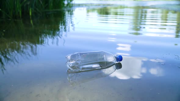 Transparent Plastic Bottle Floats Near the Shore in the River