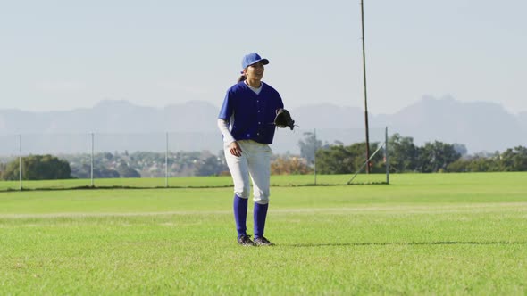 Caucasian female baseball player, fielder jumping and catching ball on baseball field