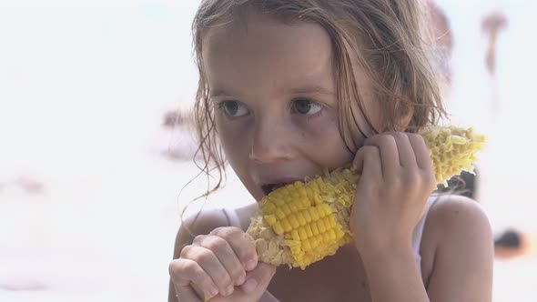 Cute Little Girl with Big Brown Eyes Gnaws Big Corncob