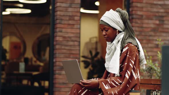 Islamic Woman Using Computer Outdoors