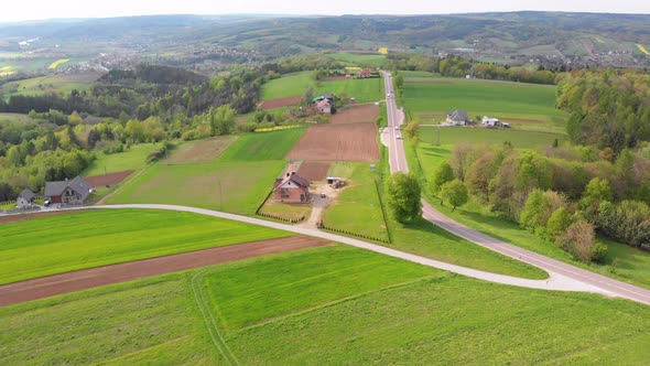 Aerial Drone View of Green Fields, Hills and Trees in a Village with Small Houses. Poland.