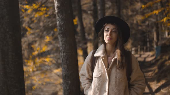 Woman Tourist Walks on Trail in Fall Forest on Sunny Autumn Day