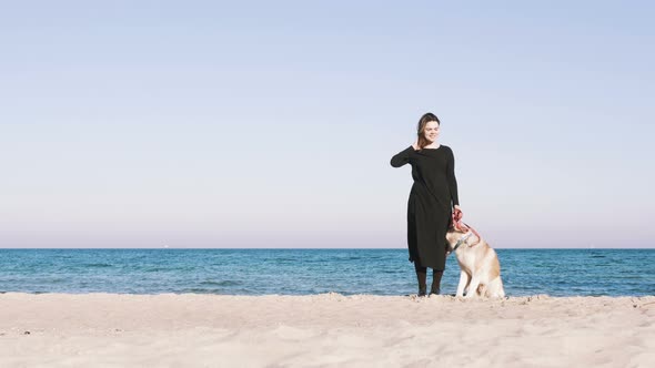 Young Female Standing with Siberian Husky Dog with Beach Background