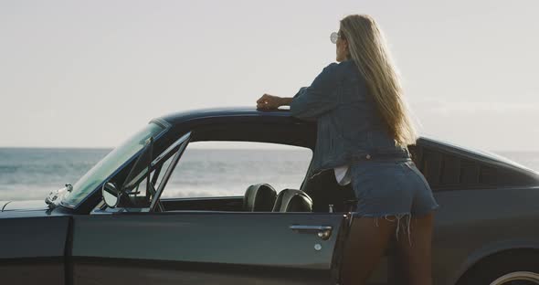 Beautiful woman posing with a vintage sports car