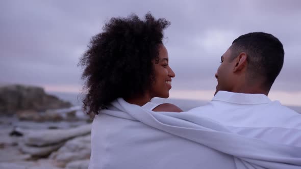 Couple wrapped in blanket on beach 4k