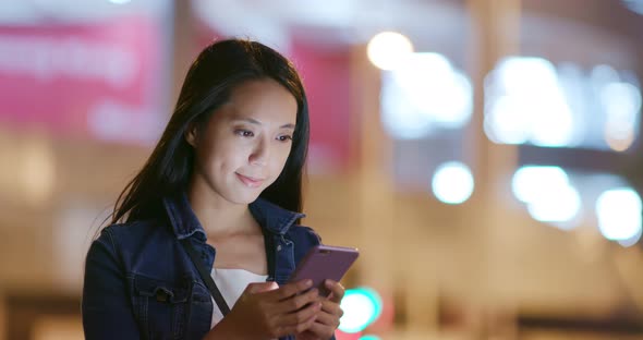 Woman use of smart phone in city at night