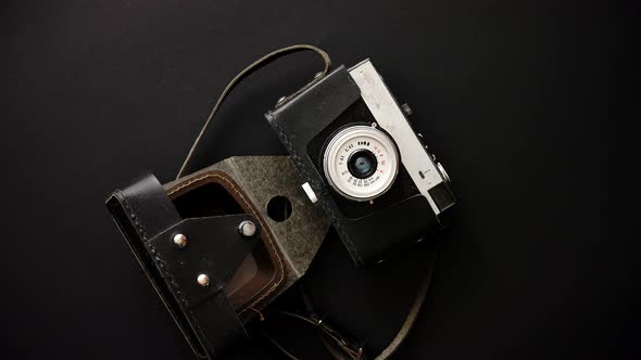 Old Retro Film Camera in Leather Case on Black Background