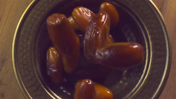 Dates fall down into copper dish in slow motion