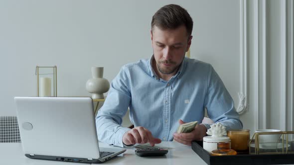 Man with Money and a Calculator Checks Bills Calculates Expenses Studies the Credit Balance Sitting