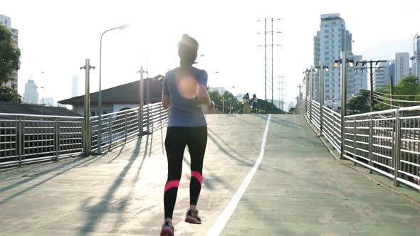 Female young Asian athlete running on the street in the city.