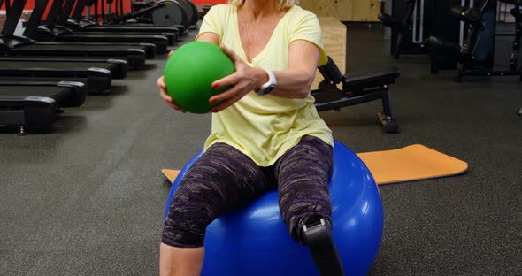 Senior woman doing abs workout with exercise ball