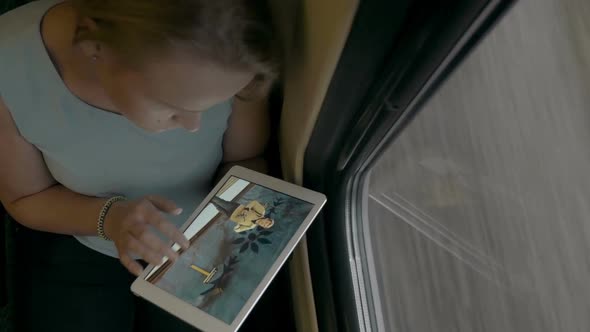 Young Girl with Tablet PC Looking at Photos in Train