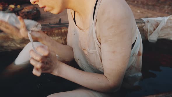 Woman Cleaning Face in Bath with Dirty Water in Dystopian World