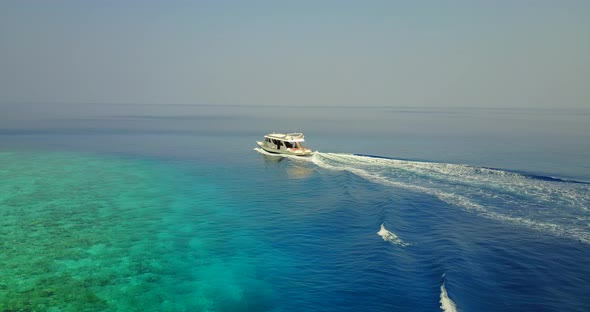 Beautiful flying travel shot of a sandy white paradise beach and aqua blue ocean background 