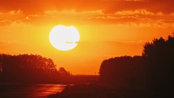 Big Sun in Vivid Beautiful Sunset Sunshine Above Summer Landscape Counrty Road And Forest