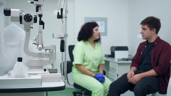 Closeup Autorefractor in Hospital with Blurred Doctor and Patient Talking at Background