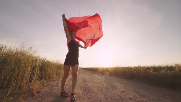 Woman with Pieces of Red Cloth Dance Near the Field with Wind Generators 