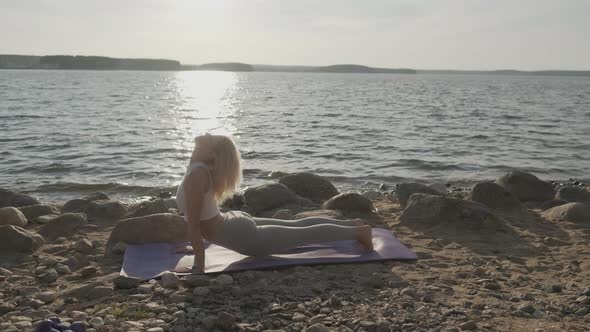 The Beautiful Athletic Woman Doing Morning Exercises on the Seashore. Beach and Sunrise on the