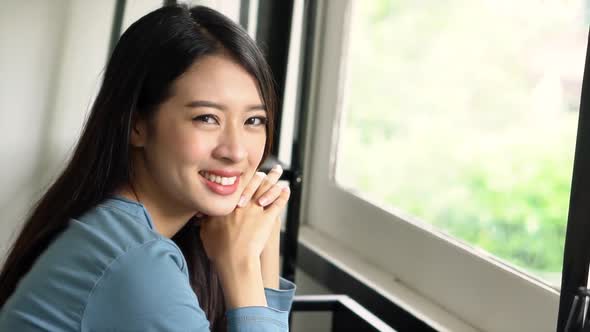 Beautiful portrait young asian woman sitting on chair by the window with smile.