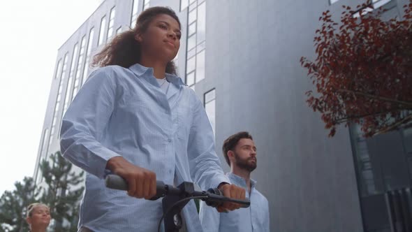 Attractive Businesswoman Riding Electric Scooter in Downtown District Going Away