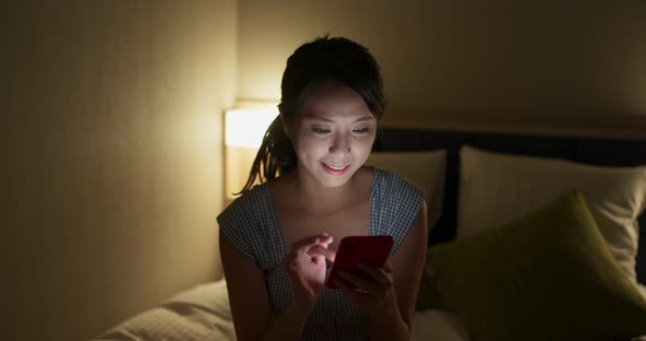 Woman use of mobile phone at bedroom in the evening