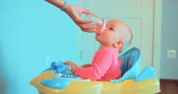 Mom's Hand Holds a Bottle of Water or Juice Baby Drinks