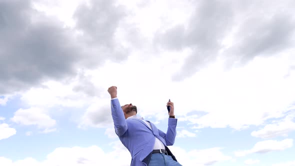 Excited Businessman with Cellphone Scream Making Winning Gesture on Sky Excitement