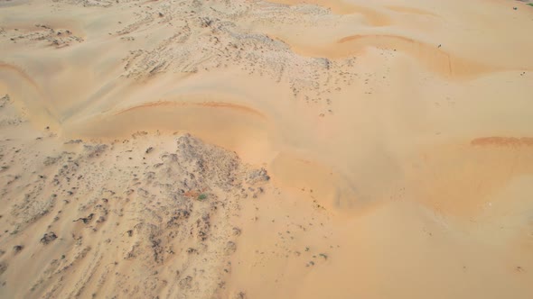 aerial pan down of dry and rocky sand dune landscape in the desert