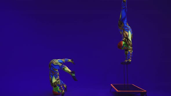 An Acrobat In A Luminous Fluorescent Body Art Performs A Stand On One Arm In A Bend