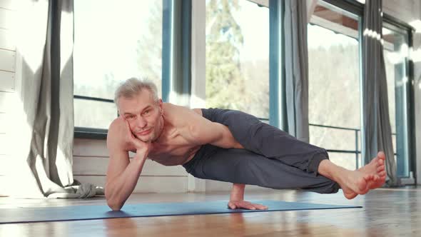 Mature Man Amongst Doing Power Yoga Exercises.