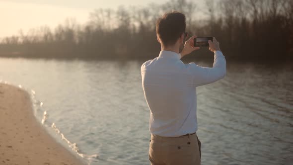 Man Takes Pictures Smartphone On City Beach. Handsome Male Taking Mobile Photo Recording Video.