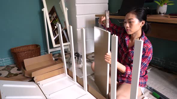 Asian woman assembling furniture at home