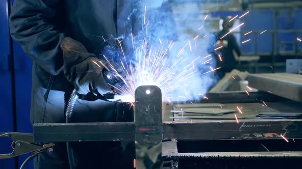 Piece of Metal Is Getting Welded By a Professional. Professional Welder Working at Factory Facility.