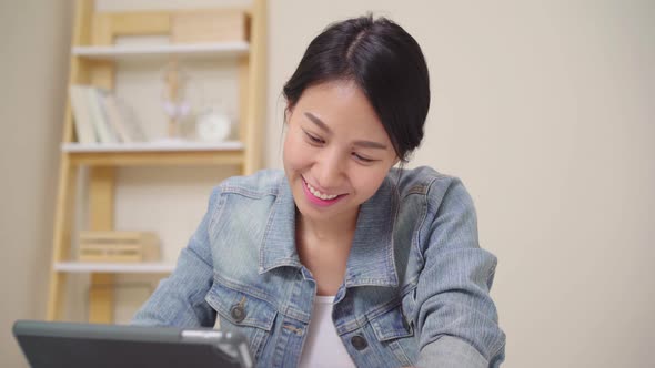 Young asian woman working using tablet checking social media while relax on desk .