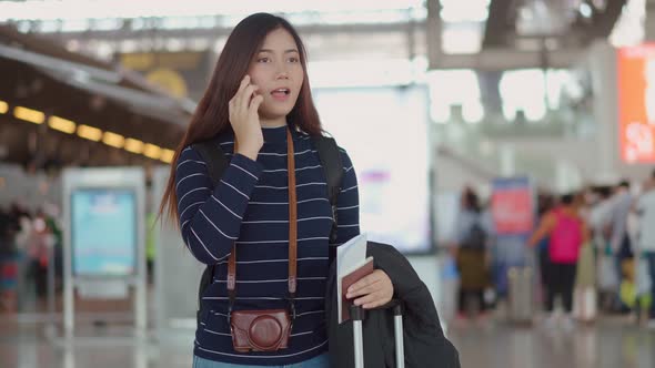 Young female traveler talking with smartphone to someone at airport