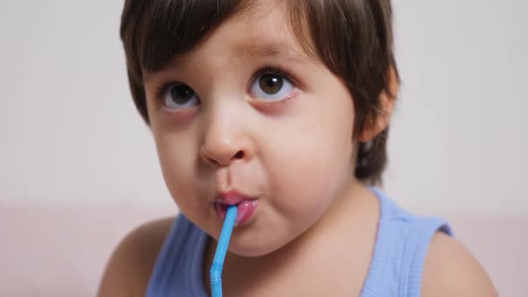 Baby Boy in Blue T-shirt Sitting on the Bed at Home and Drinking Milk