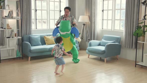Asian Father Ride Dinosaur Toy With His Son In Modern House Living Room, Happy Family