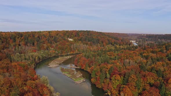 Wonderful autumn colors: Drone shot of a river with little islands leading through a colorful forest