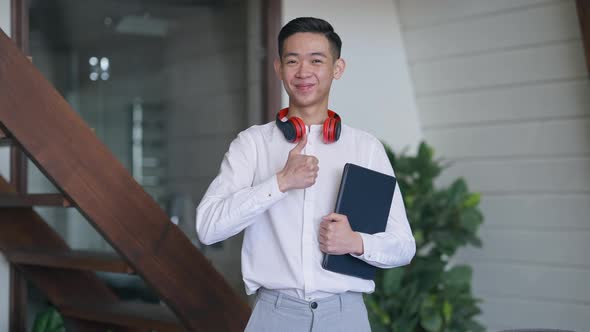 Middle Shot of Happy Smiling Chinese Man Showing Thumb Up Looking at Camera Standing in Living Room