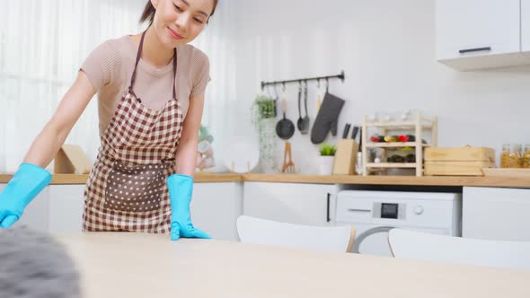 Asian young cleaning service woman worker clean kitchen table at home.