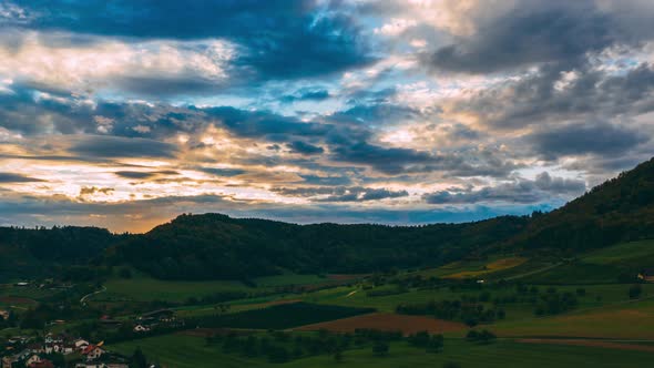 aerial hyperlapse of countryside with dramatic sunset, fast moving clouds in switzerland