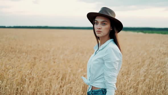 Beautiful Girl in a Shorts and Hat Walking Through a Wheat Field at Sunset. Freedom Concept. Wheat