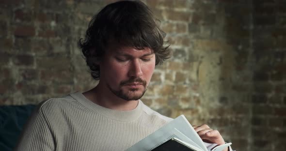 A Young Bearded Man is Carefully Reading an Interesting Book