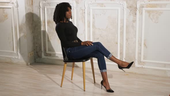 Exciting Black Lady in Blue Jeans Sits on Brown Wooden Chair