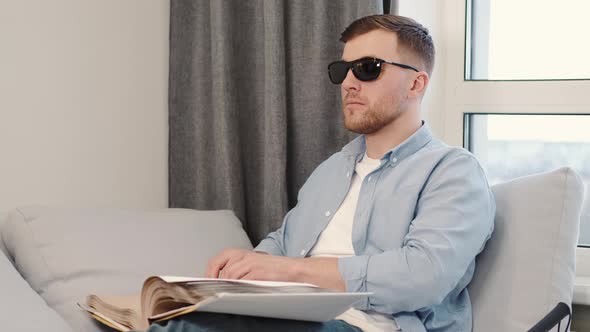 Blind Young Man Reading Braille Book on Couch