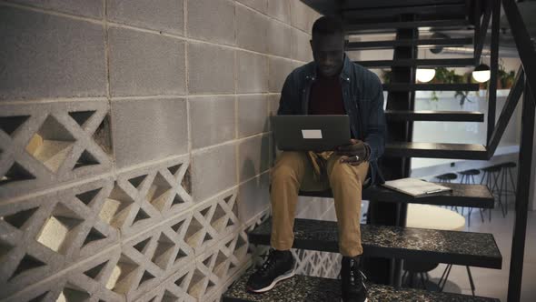 Man with laptop on stairs in office