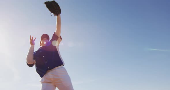 Mixed race female baseball fielder catching and throwing ball on sunny baseball field