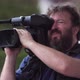 Bearded television cameraman filming outdoors. - VideoHive Item for Sale