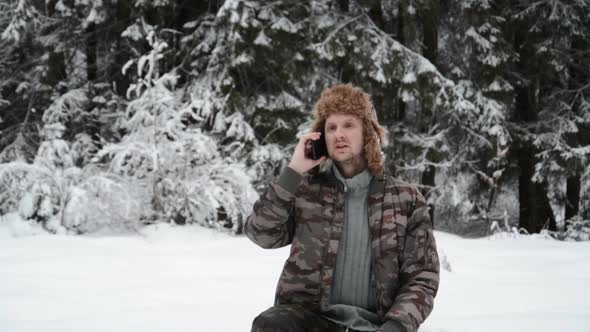 Funny Young Man Portrait in a Snowy Forest Talking on the Phone