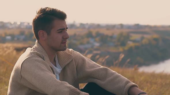 Handsome Lonely Guy Sits on River Bank in Autumn Close Slow